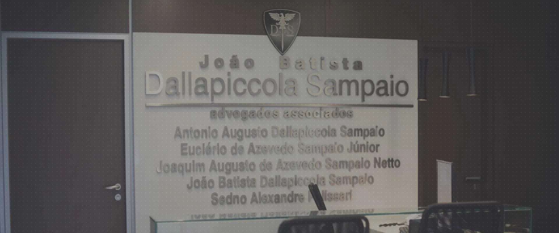 Recepção do escritório, com o nome em letras de metal na parede